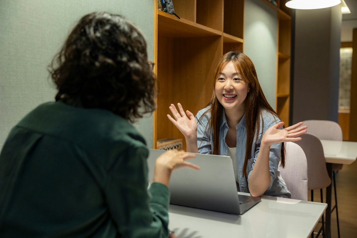 Woman discusses business with colleague at a laptop.